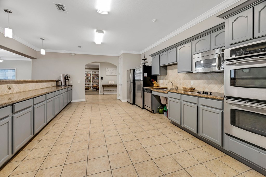 a large kitchen with stainless steel appliances and tiled floors