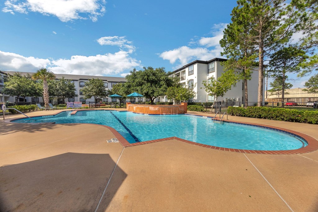 a swimming pool with trees and a building in the background