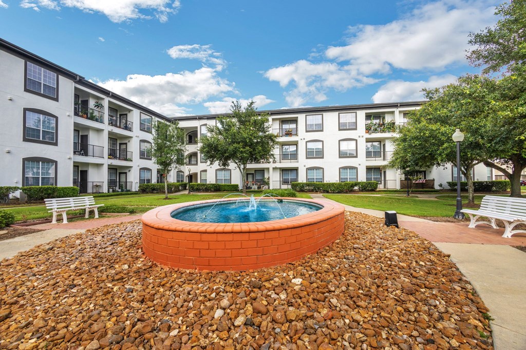 an exterior view of an apartment building with a pool and rocks