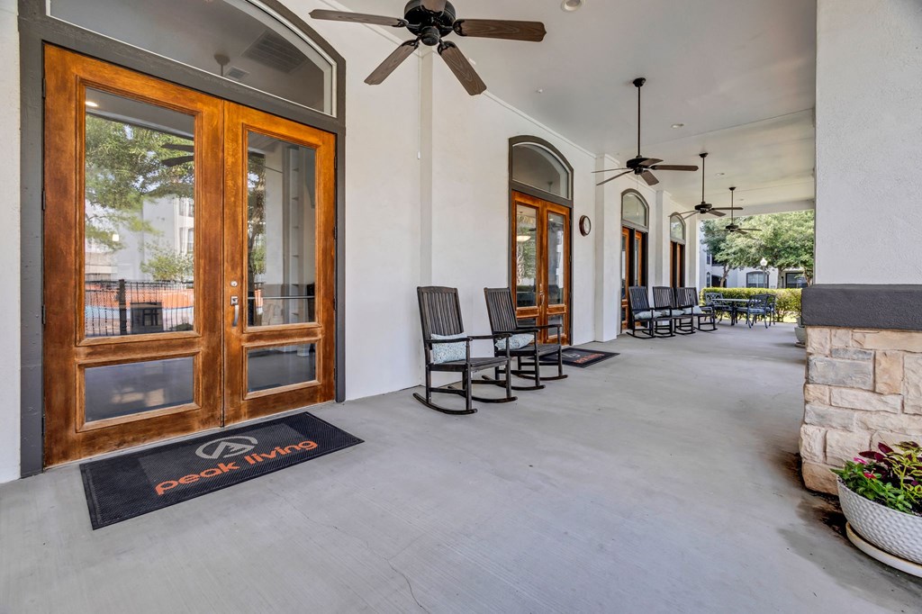 a long porch with rocking chairs and a ceiling fan
