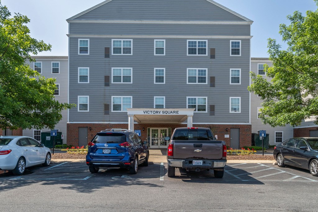 a parking lot with cars in front of an apartment building