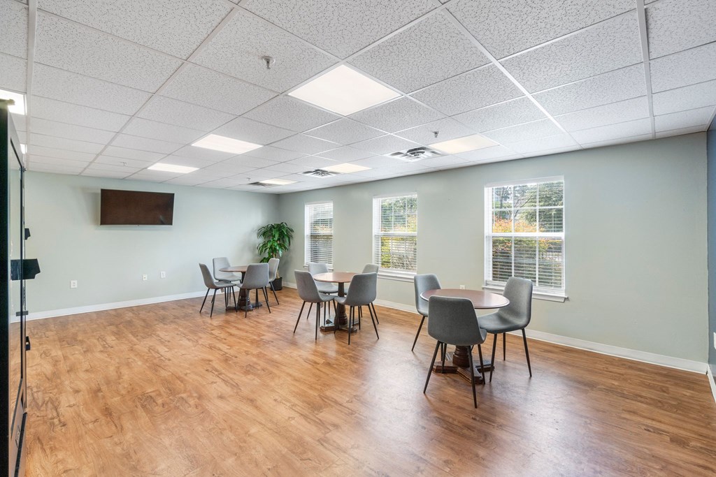 a conference room with tables and chairs and a wall mounted tv