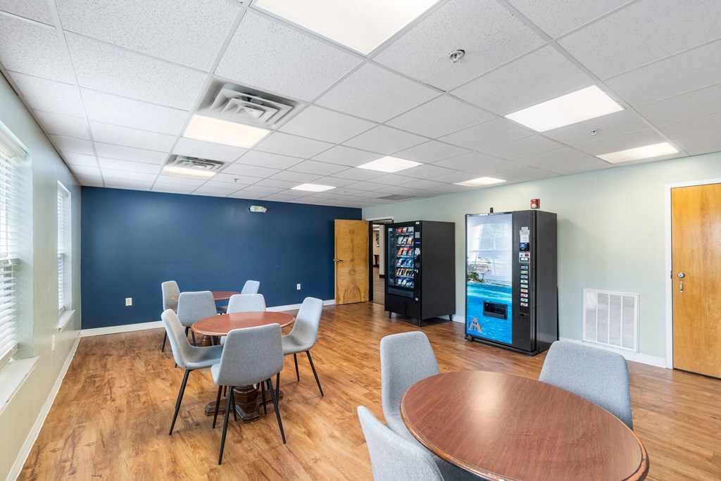A room with a table and chairs and a vending machine.