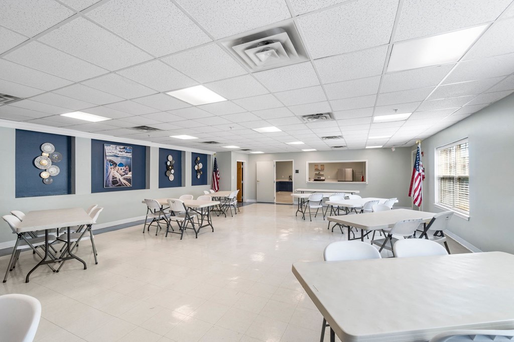 A room with tables and chairs and flags on the wall.