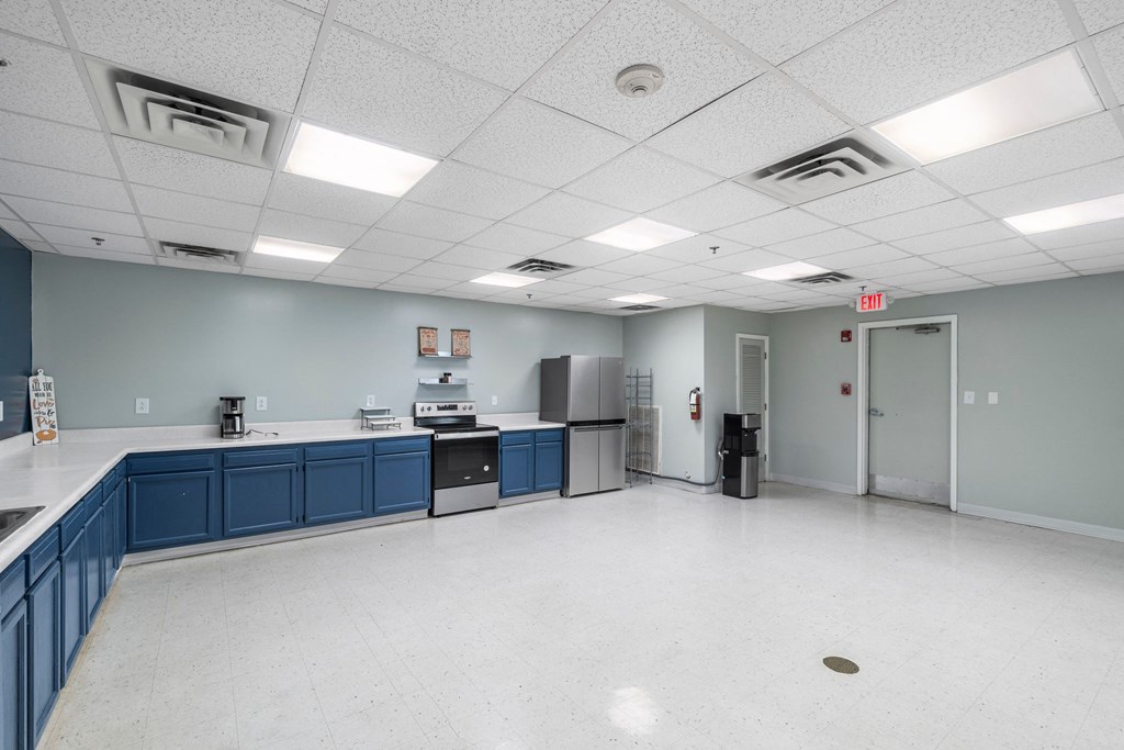 A large, empty room with blue cabinets and white flooring.