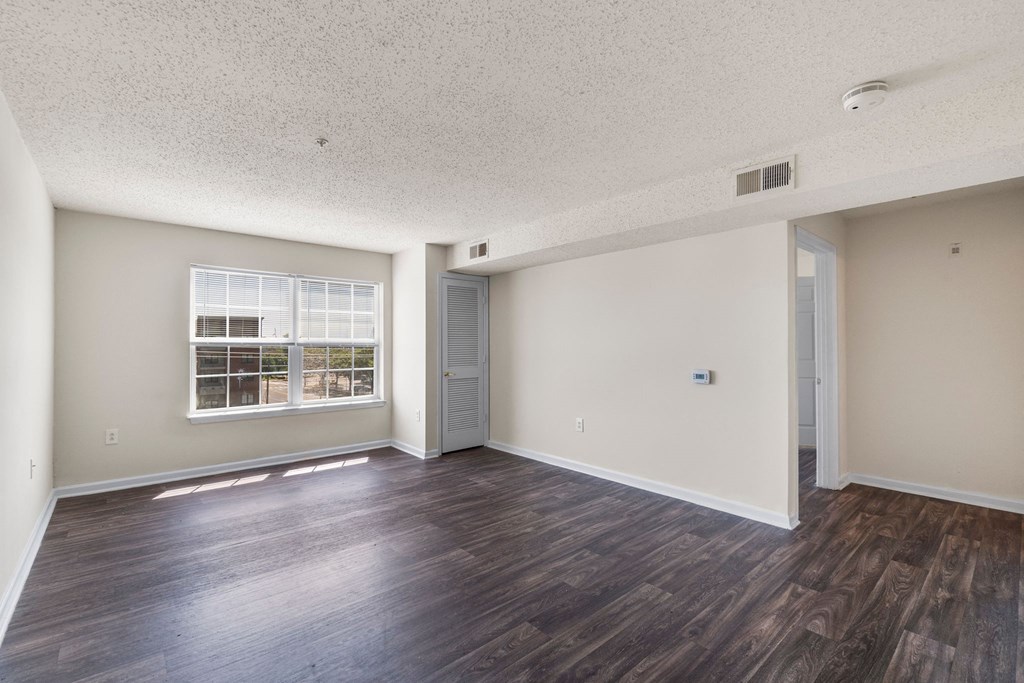 an empty living room with hard wood flooring and a window