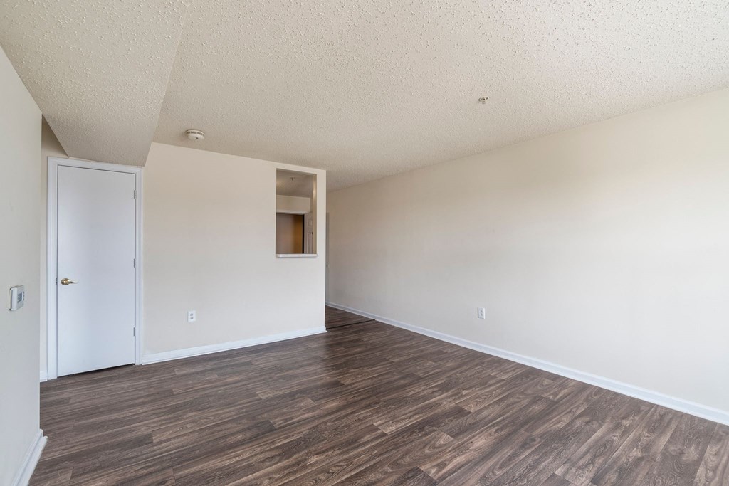 an empty living room with white walls and wood floors