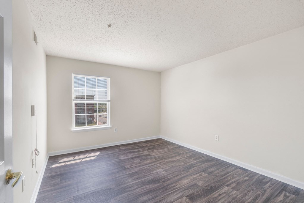 an empty living room with a window and wood flooring