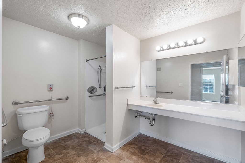 A white bathroom with a toilet, sink, and mirror.