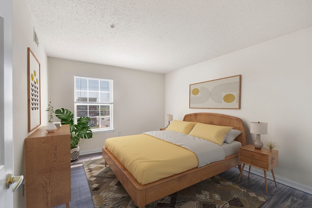 A bedroom with a bed, nightstand, and a plant.