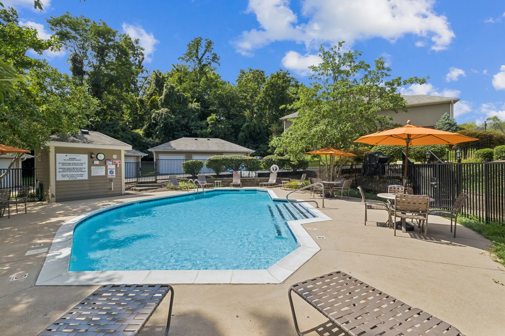 A pool surrounded by trees and a building in the background.