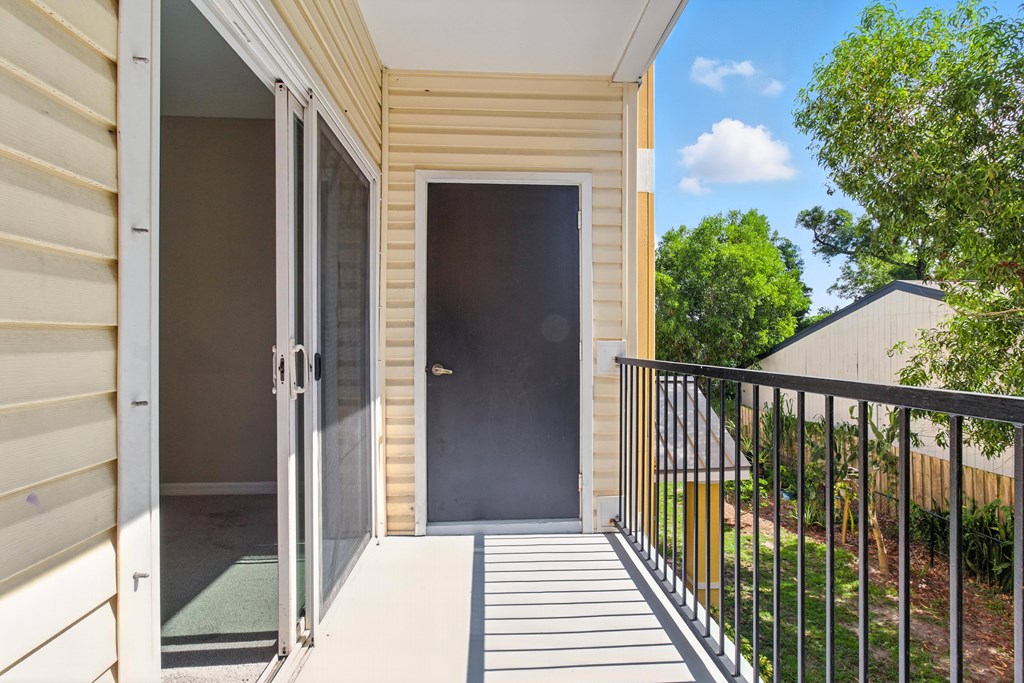 A balcony with a black door and a metal railing.