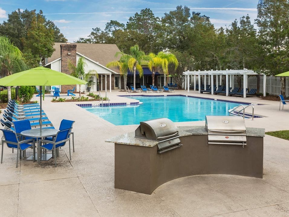 a swimming pool with chairs and a bar with a grill