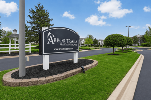 A sign for Arbor Trails Apartment Homes stands in a grassy area.