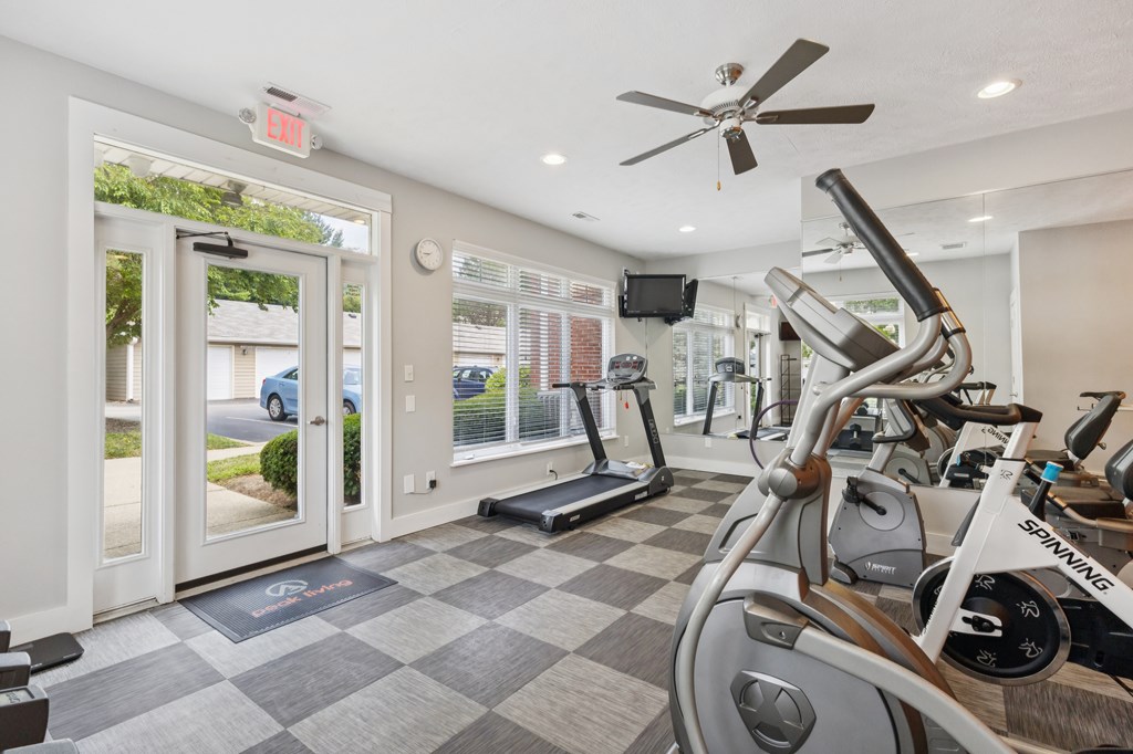 A Spinning bike is in a well lit gym with a checkerboard floor.