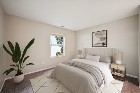 A bedroom with a large bed and a potted plant.