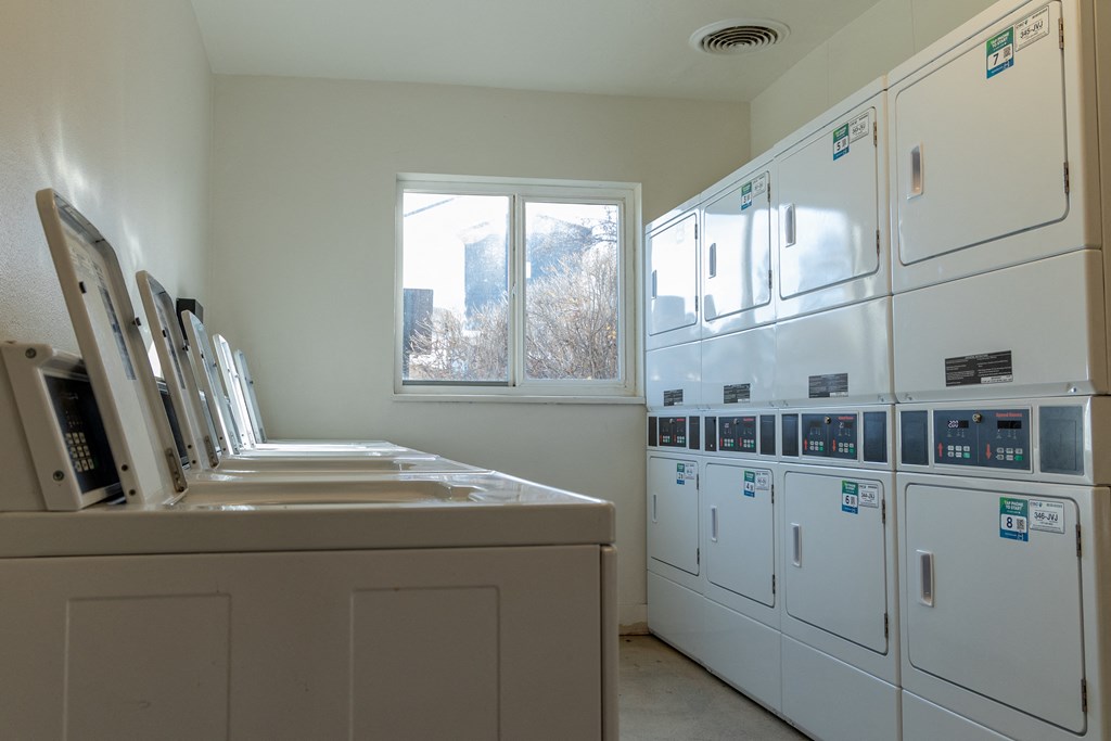 a laundry room with many white machines and a window