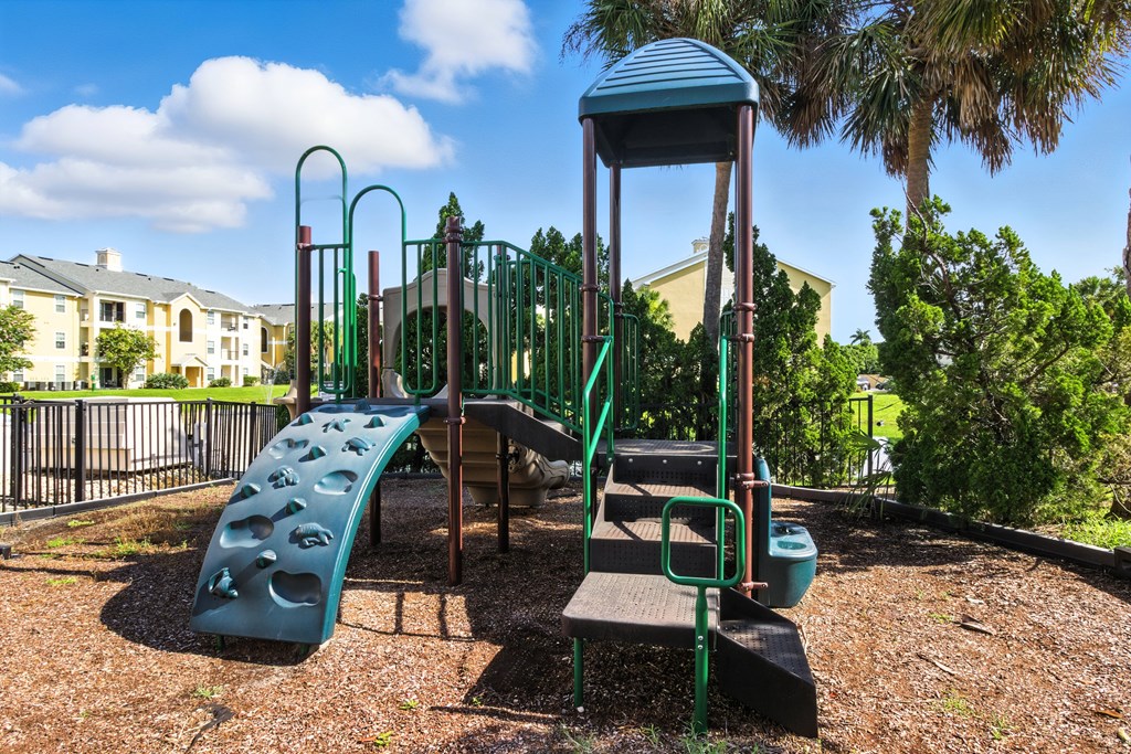 A playground with a green slide and a brown wooden platform.