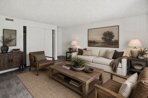 A living room with a white couch, a wooden coffee table, and a painting on the wall.