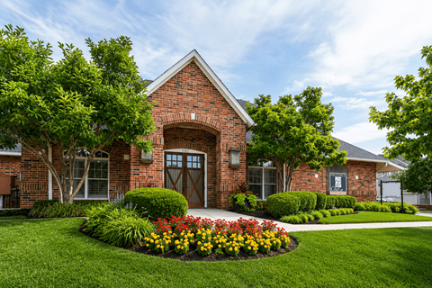 A brick building with a flower bed in front.