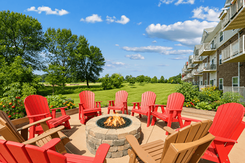 A fire pit surrounded by red chairs on a patio.