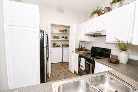 A kitchen with white cabinets and a black stove top oven.