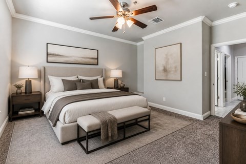 A bedroom with a large bed and a ceiling fan.