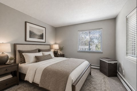 A bedroom with a large bed and a window with blinds.