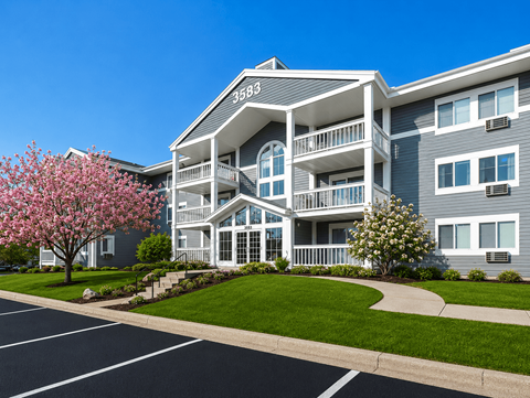 A large apartment building with a tree in bloom in front of it.