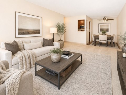 A living room with a white couch, a coffee table, and a painting on the wall.