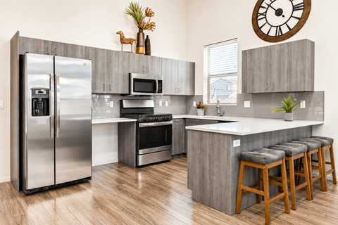 A modern kitchen with a refrigerator, oven, microwave, and bar stools.