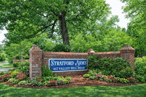 A sign that says Stratford Arms stands in front of a tree.