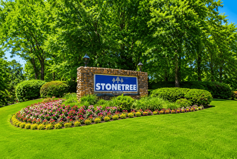 A sign that says Stone Tree in front of a green lawn.