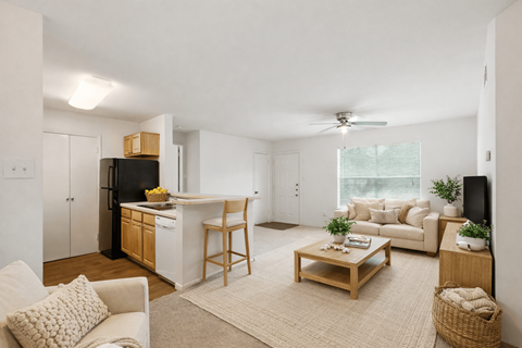 A well-lit, spacious living room with a kitchen area in the background.