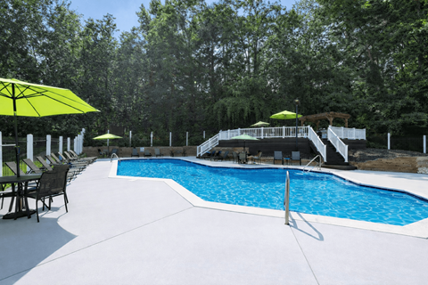 A pool with a white fence and trees in the background.