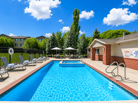 A swimming pool surrounded by lounge chairs and umbrellas.