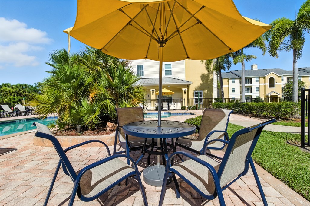 A table with chairs and an umbrella is set up outside.