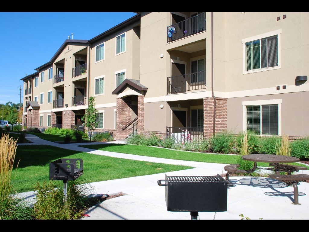 an exterior view of an apartment building with a patio and picnic table