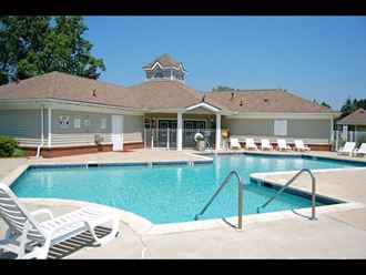 a large pool with lounge chairs and a building in the background - Photo Gallery