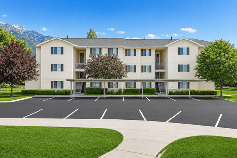 A large apartment complex with a parking lot in front.