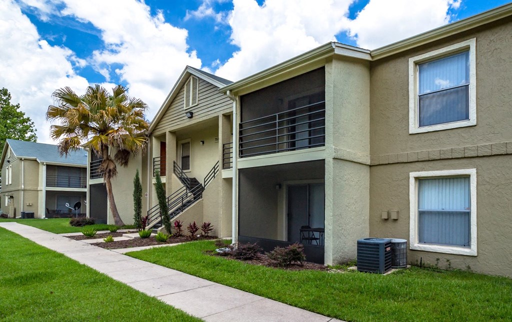 a sidewalk in front of an apartment building with a palm tree