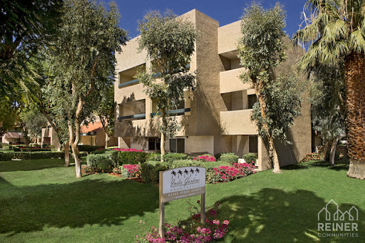a garden in front of a building with trees and a sign
