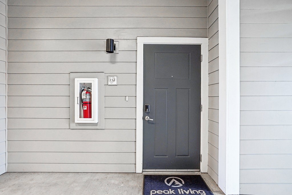A grey door with a black mat that says Peak Living on it. at Connect at First Creek Apartments, Denver