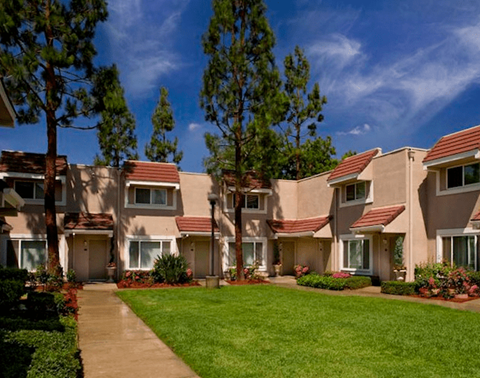 a row of apartments with green grass and trees