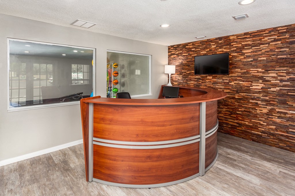 a reception area with a wooden reception desk and a brick wall