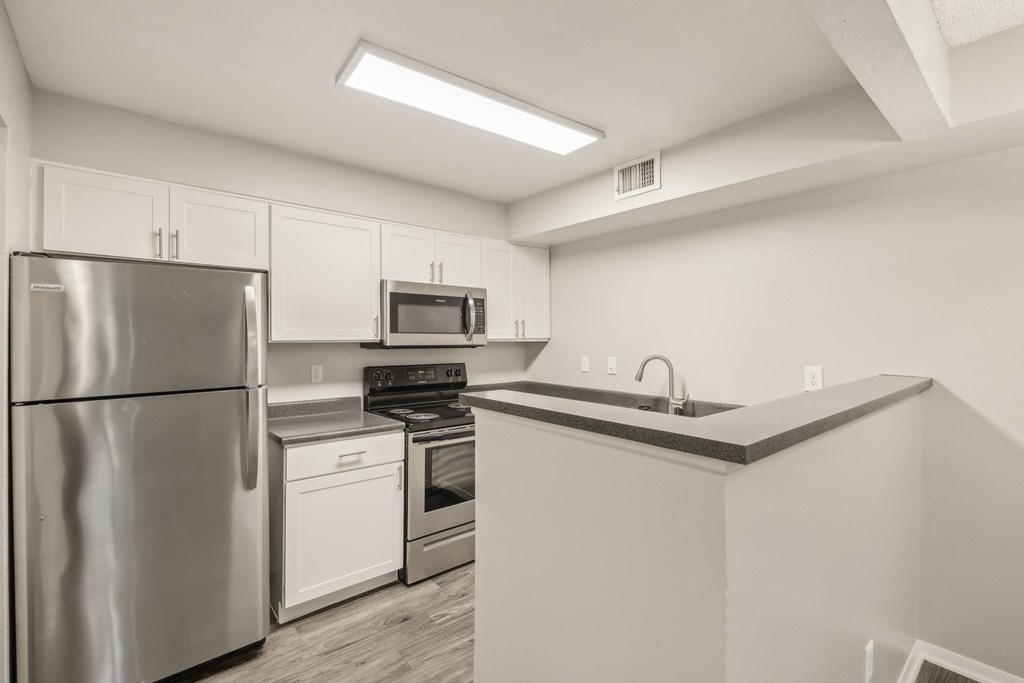 A kitchen with a stainless steel refrigerator, microwave, oven, and dishwasher.