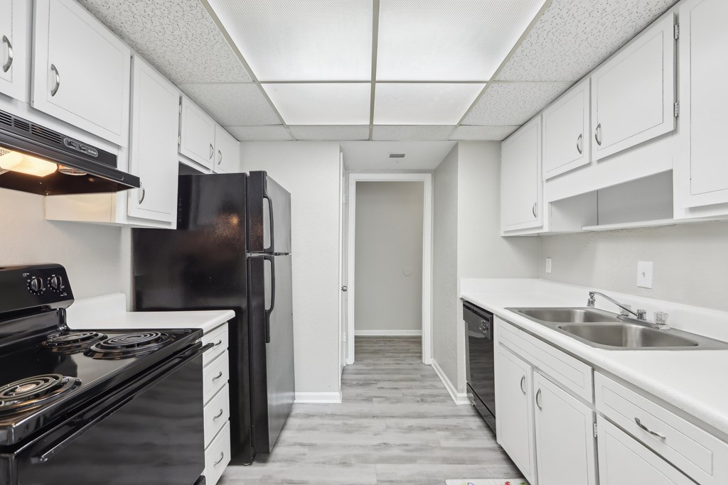 A kitchen with black appliances and white cabinets.