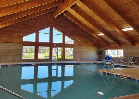 the indoor pool of a resort with a wooden ceiling and glass windows