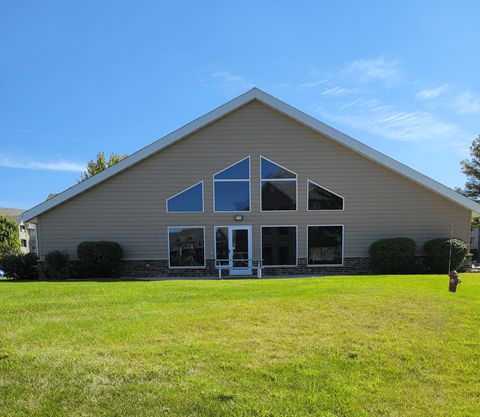 a view of the front of a church with a grass field in front