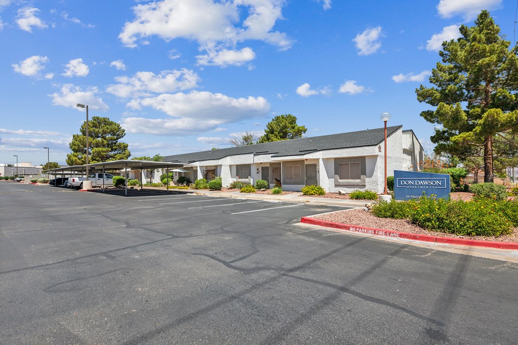 an empty parking lot in front of a white building with a blue sign